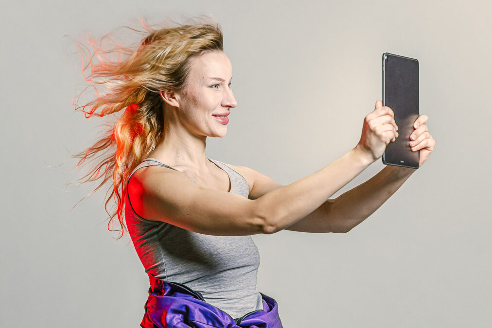 Nuori nainen katselee tablettia opiskelijahaalarit päällään.